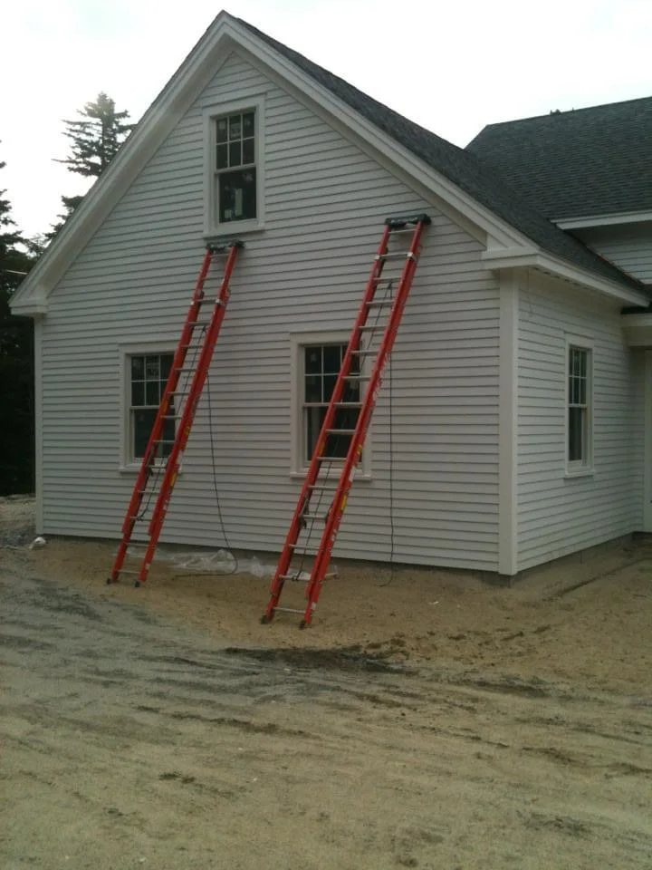 New England-style home undergoing exterior painting, with ladders set up for fresh white siding and trim application. Expertly painted by T&B Paint Pros. tbpaintpros Flagler County Florida experienced painter, specializing in exterior home painting and restoration.