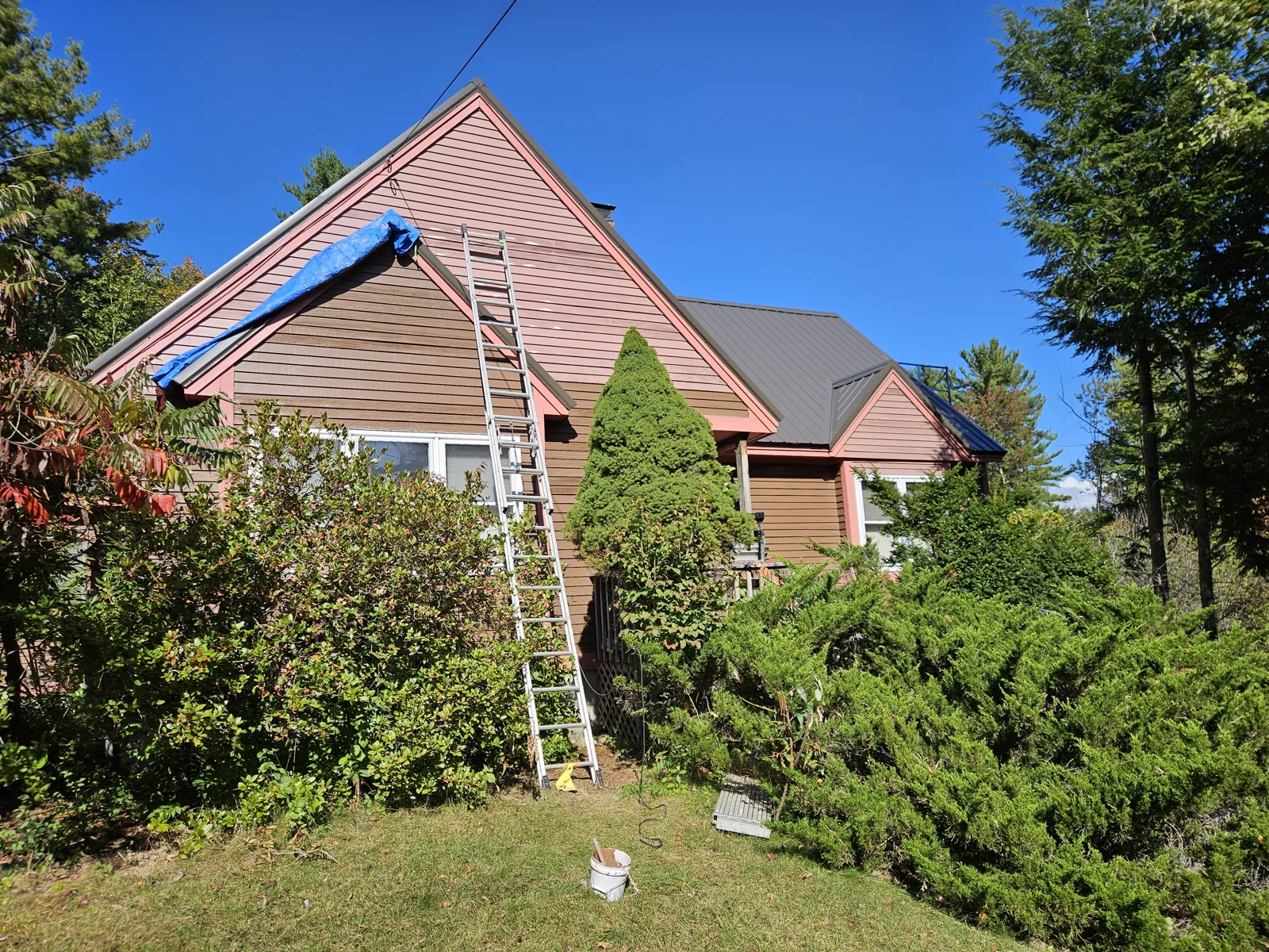 Exterior home painting in progress—upper portion freshly painted red, lower portion brown. Professional work by T&B Paint Pros. tbpaintpros Flagler County Florida experienced painter, ensuring high-quality, durable home transformations.